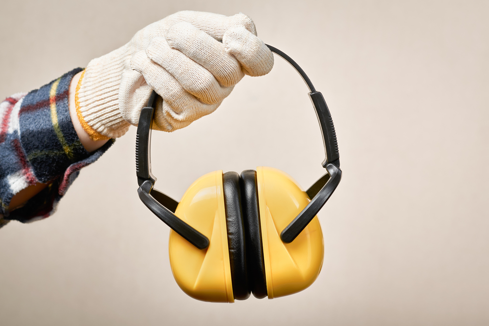 Manufacturing worker holds earphones for noise protection